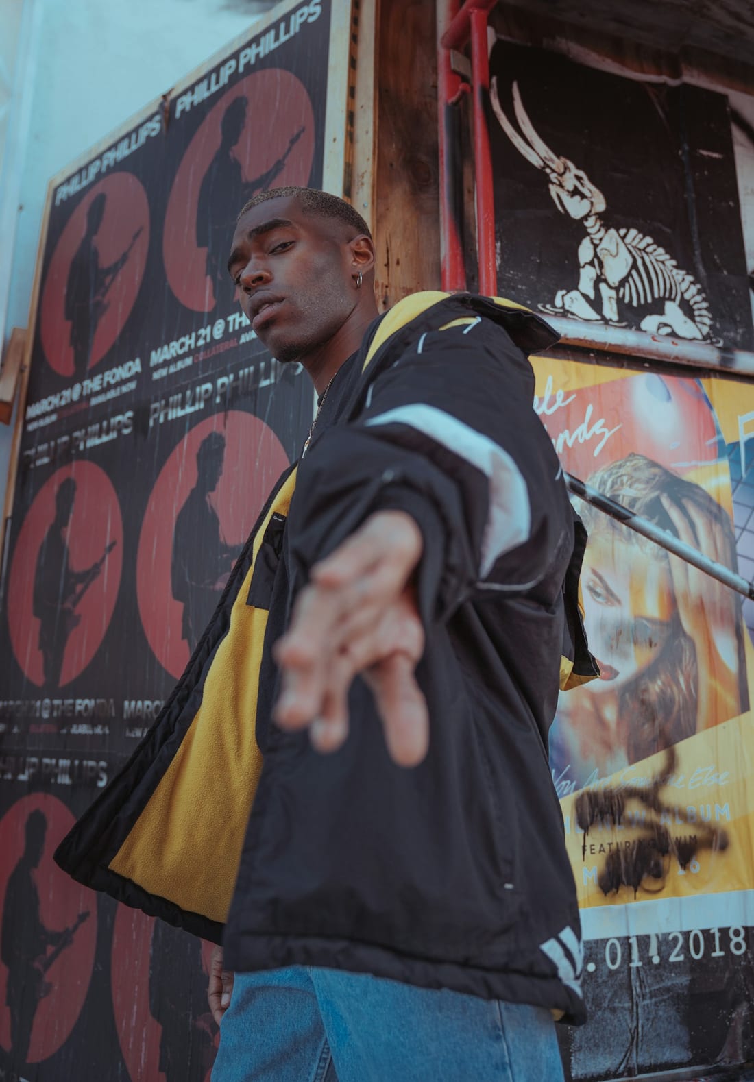 Black jacket layered over a yellow shirt with blue jeans